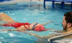 Swim coach teaching adult swimmer how to float